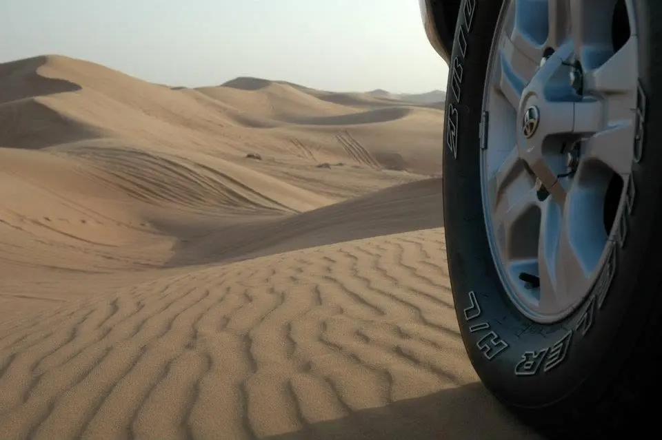 Geländewagenrad vor Sanddünen bei Dubai