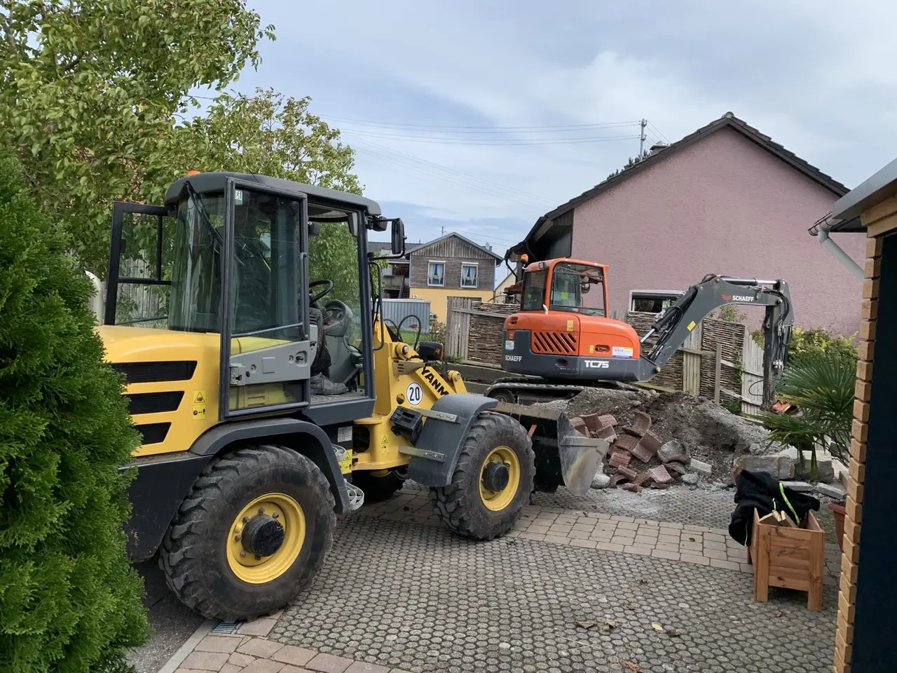 Radlader und Bagger entfernen Pflaster und Erde