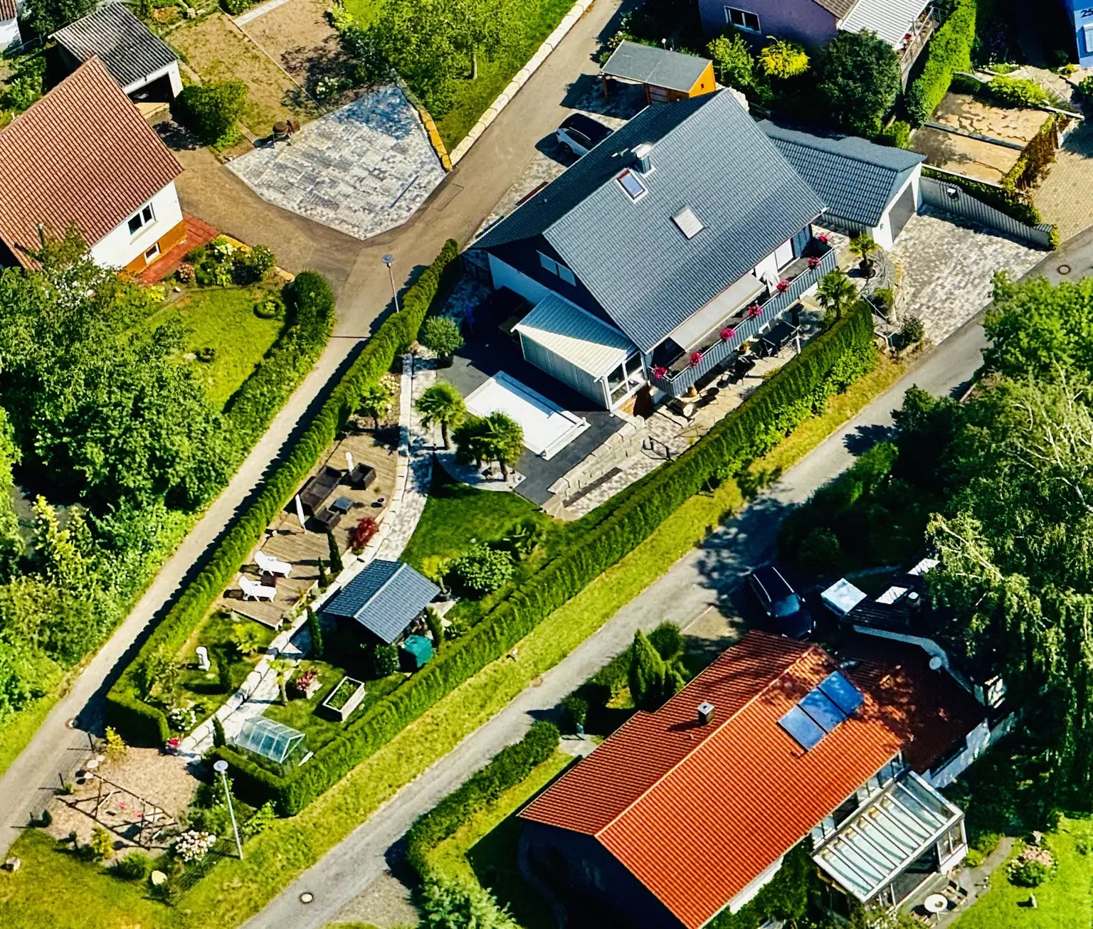Luftaufnahme des Hauses und des vollständig umgebauten Gartens mit Pool, Wegen und verschiedenen Sitzbereichen