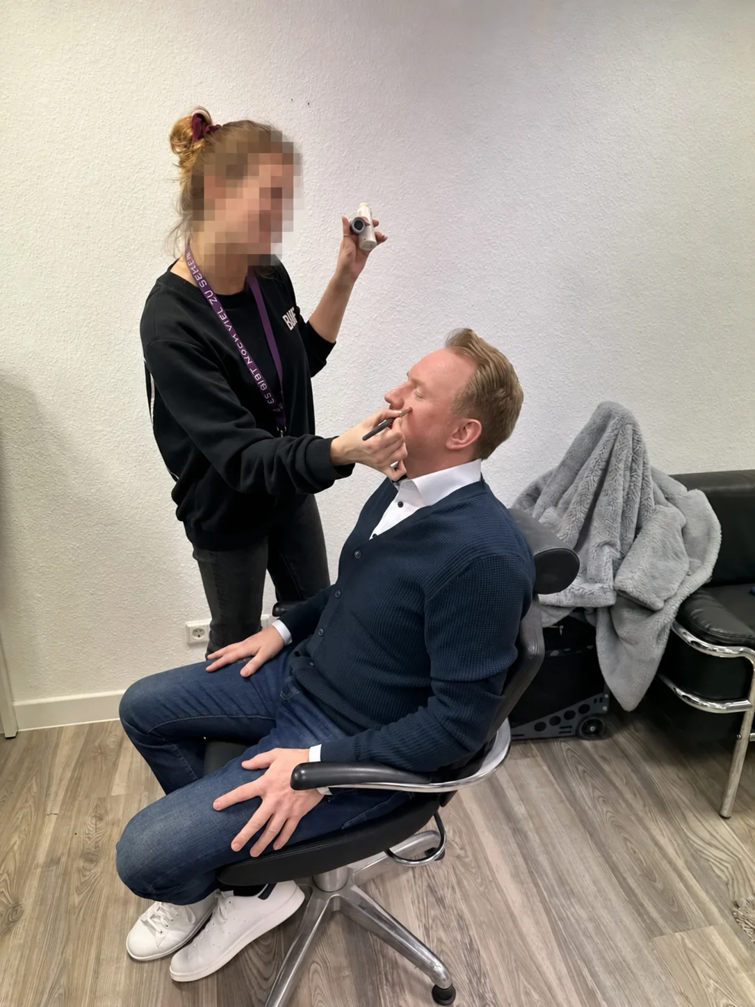 Marcus sitzt vor einem Dreh in der Maske; die weitere Person ist vollständig unkenntlich gemacht